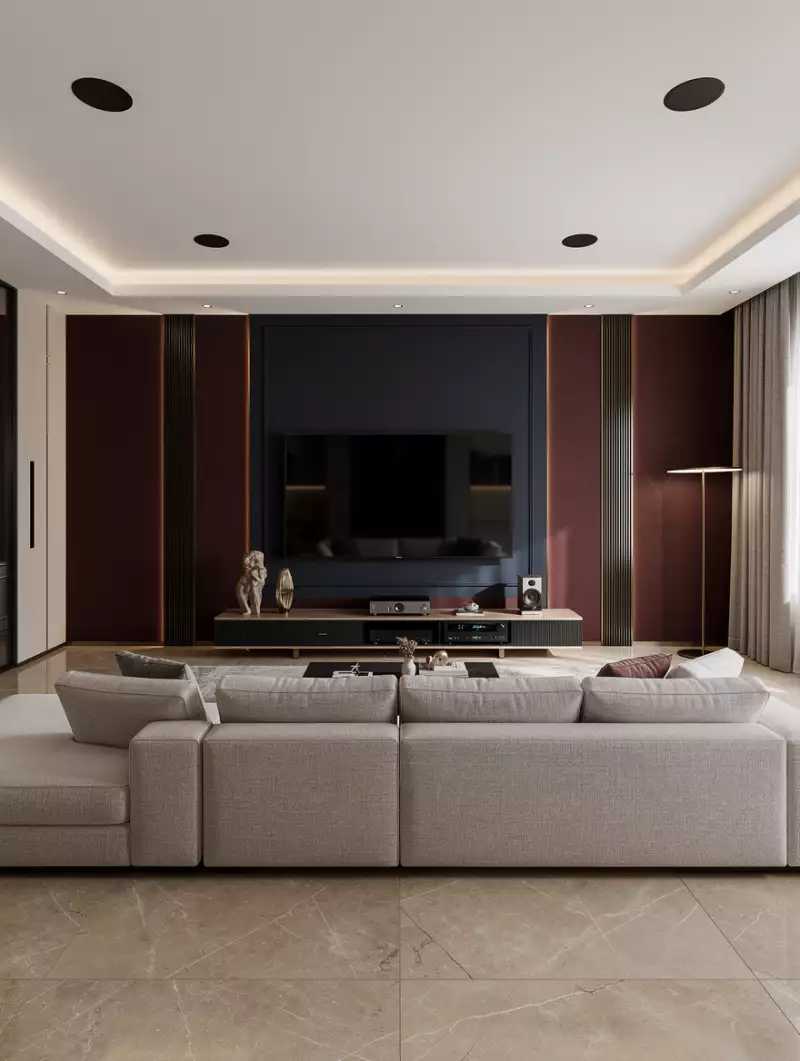 Сгенерировано нейросетью: Modern classic living room interior, large 85-inch TV on a dramatic accent wall, deep navy or burgundy wall panels with dark brushed brass inlays, G-shaped sectional sofa in premium fabric, cinematic Dolby Atmos ceiling speakers (4 overhead speakers), warm LED indirect lighting, stone floor with beige warm marble tiles, luxurious but cozy atmosphere, high-end audio system, minimalistic but elegant design, matte textures, premium finishes, perfect symmetry, ultra realistic, 8K render, soft shadows, volumetric light